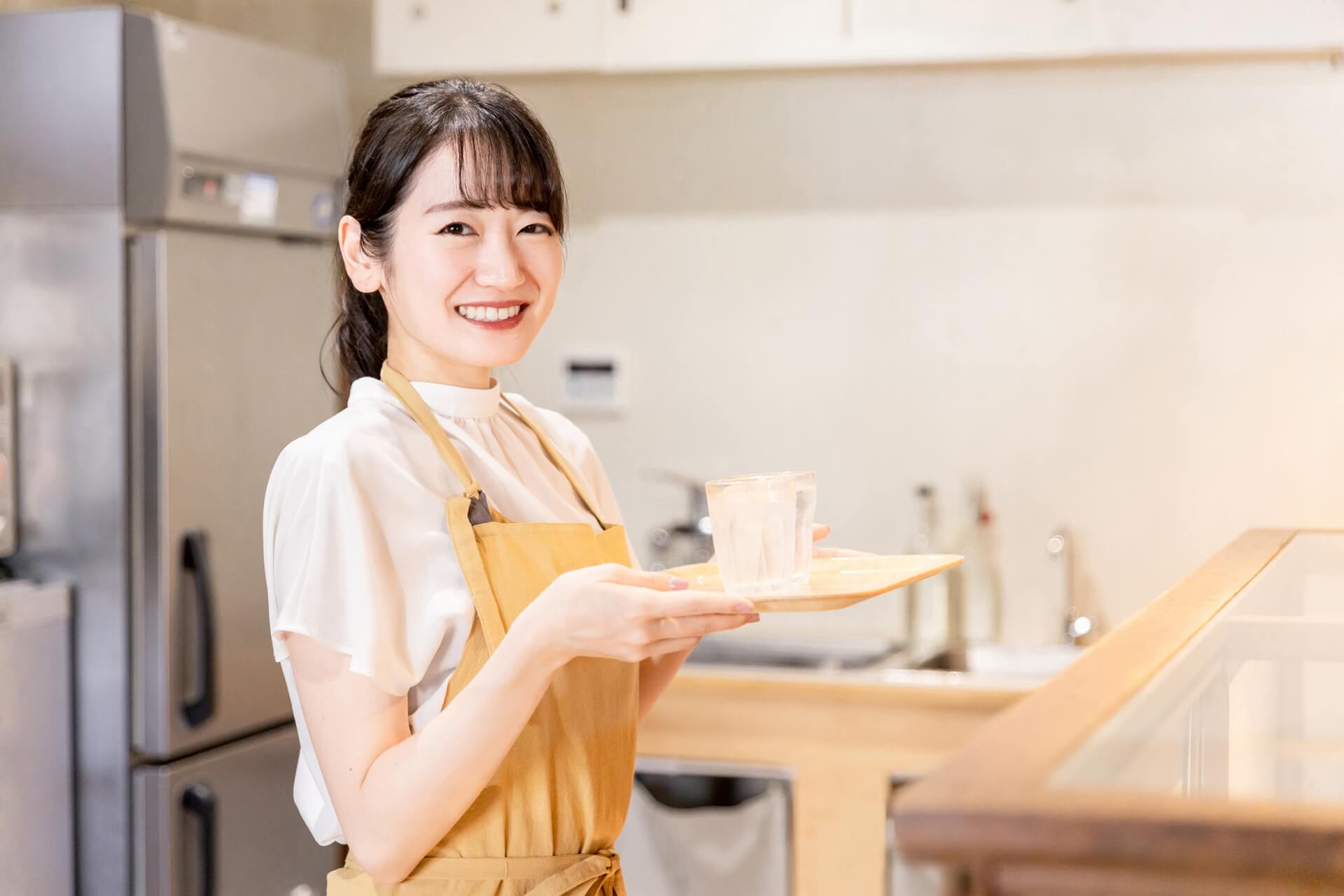 笑顔でドリンクを提供する女性スタッフの写真